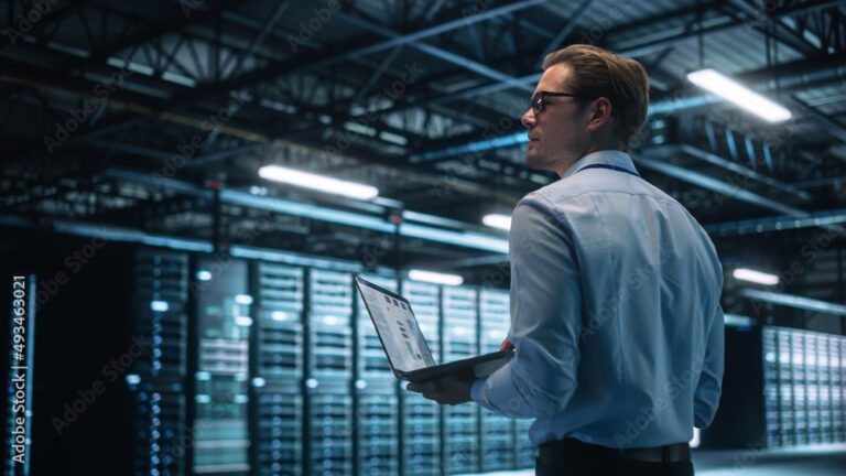 Data Center Male It Specialist Using Laptop while Working on Computer. Information Technology Professional. Server Farm Cloud Computing and Cyber Security Maintenance Concept